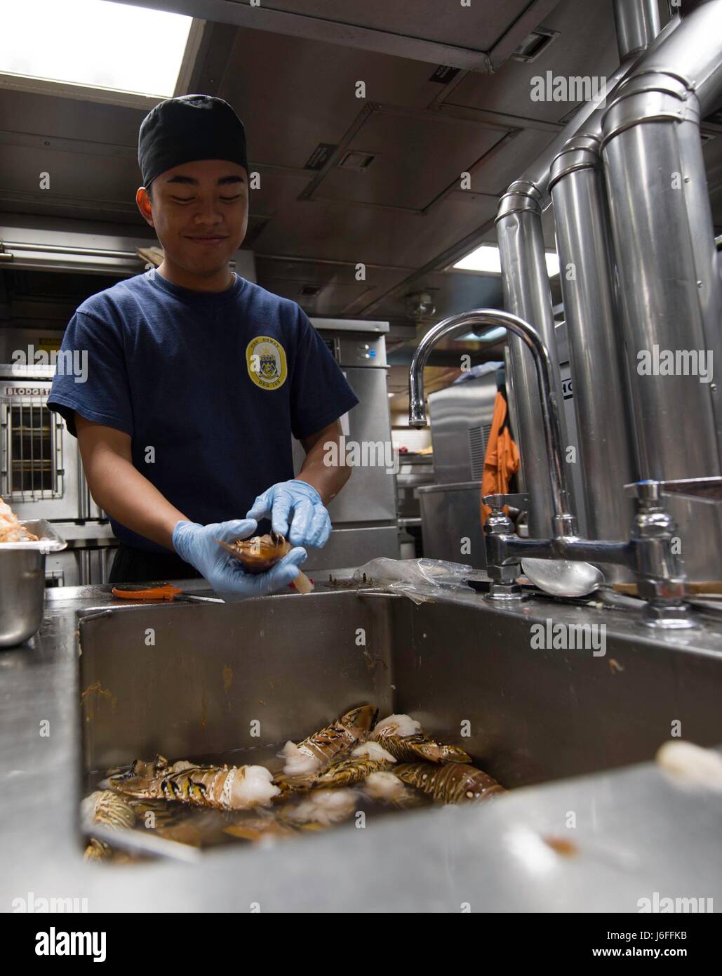 170514-N-BV658-105     SOUTH CHINA SEA(May 14, 2017)   Christianjo Bejec, a native of the Philippines, prepares lobster in the galley aboard the Arleigh Burke-class guided-missile destroyer USS Dewey (DDG 105).  Dewey is part of the Sterett-Dewey Surface Action Group and is the third deploying group operating under the command and control construct called 3rd Fleet Forward.  The U.S. 3rd Fleet operating forward offers additional options to the Pacific Fleet commander by leveraging the capabilities of 3rd and 7th Fleets. (U.S. Navy Photo By Mass Communication Specialist 3rd Class Kryzentia Weie Stock Photo