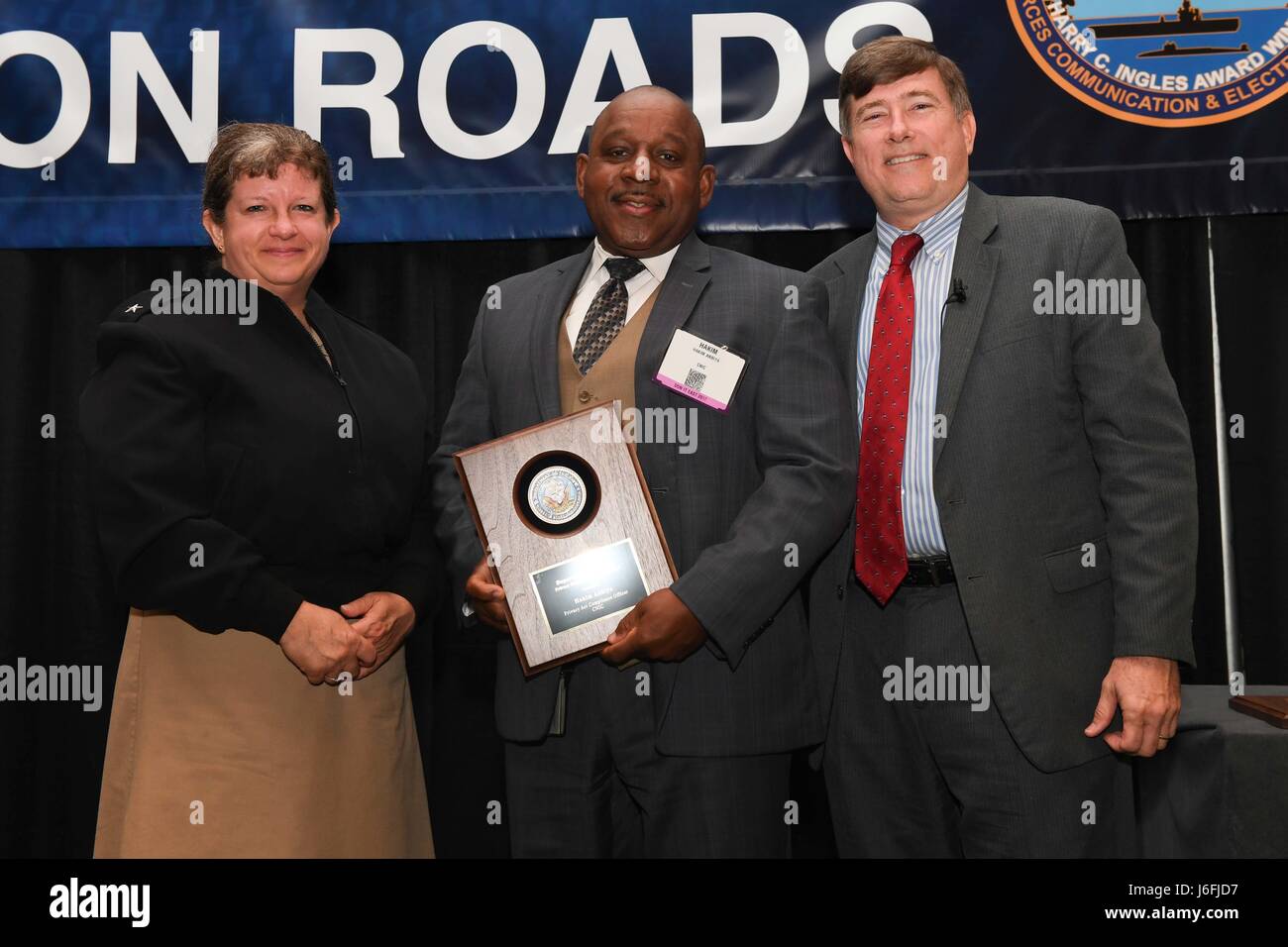 170517-N-GX781-052 NORFOLK (May 17th, 2017) - Rear Adm. Danelle Barrett, director, DON deputy chief information officer (Navy) and deputy director, Navy Cybersecurity, left, and Mr. Robert Foster, DON chief information officer, right, present the DON Privacy Program Excellence Award to Hakim Anbiya, Privacy Act compliance officer, Privacy Act Program, center. The purpose of the IT conference is to share information about new and emerging IT policy and initiatives. (U.S. Navy photo by MCSN Livingston/ Released.) Stock Photo