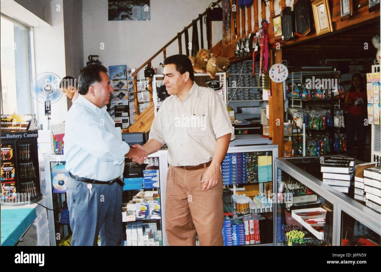Two individuals greet each other with a handshake inside a store ...