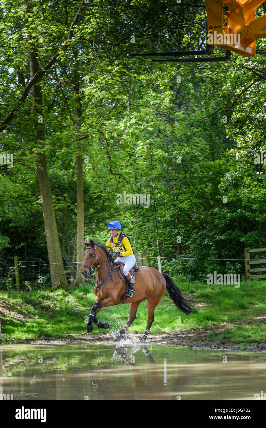 Rockingham Castle, Corby, UK. 21st May, 2017. Richard Evans and his horse Brown Sugar III pass through the water hole on a sunny day during the Rockingham International Horse Trials in the grounds of the norman castle at Rockingham, Corby, England on 21st may 2017. Credit: miscellany/Alamy Live News Stock Photo