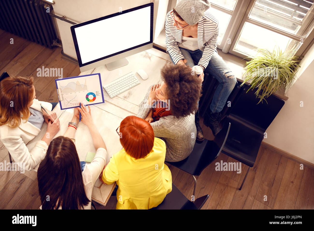 Young women at creative work with chart and computer in office Stock Photo