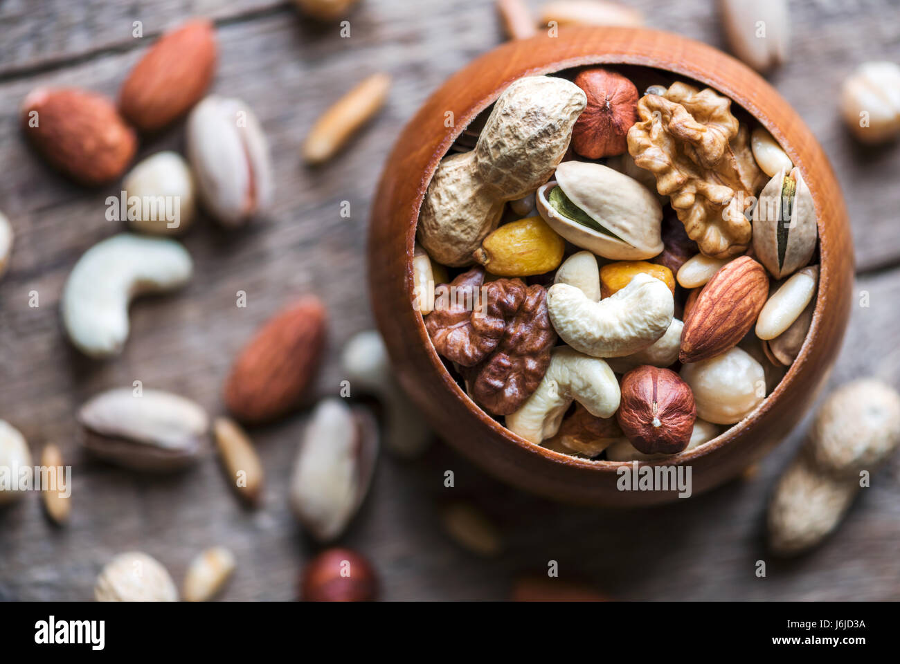 Dried mixed nuts in wooden bowl closeup. Walnut, pistachio, hazelnut, almond and other. Studio macro shoot. Stock Photo
