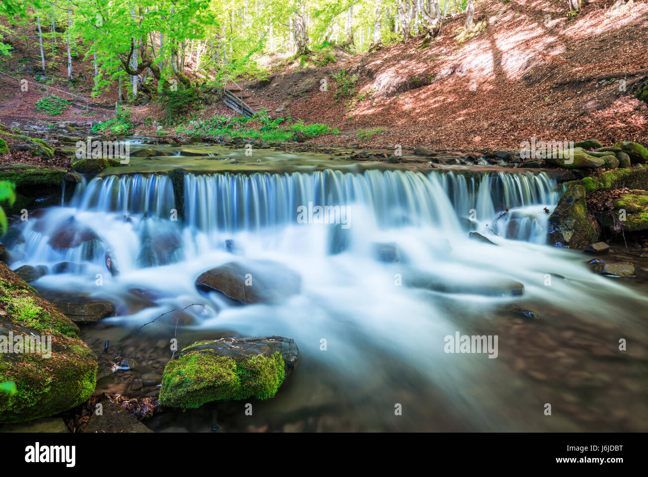 Amazing waterfall cascades in spring forest. Blue streams of running water Stock Photo