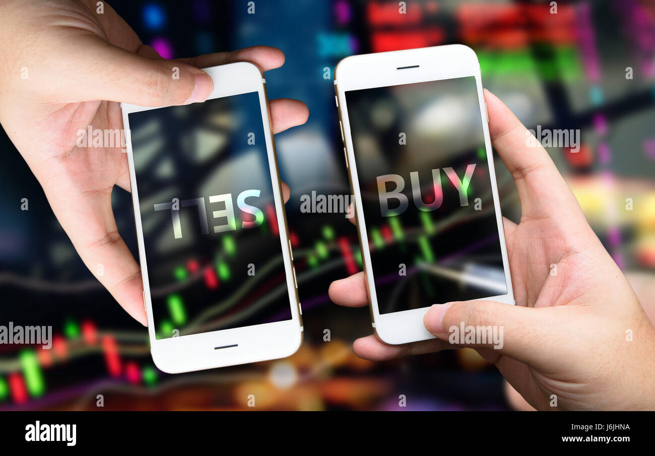 Fintech concept image. Hand holding two smart phones buy and sell stock on mobile screen. stock market concept image background Stock Photo