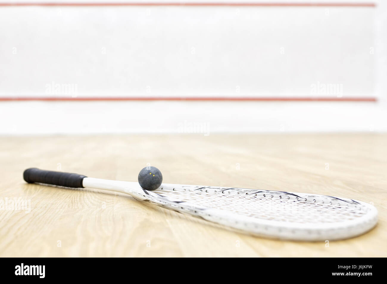 one squash racket and ball on the wooden floor. Racquetball equipment