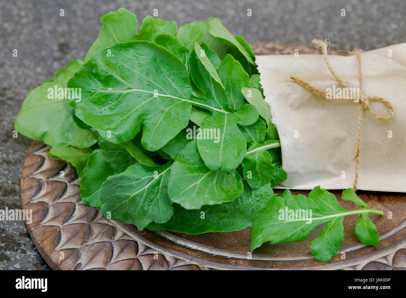 Bunche of fresh arugula, fresh rucola rocket salad leaves in a paper bag on a granite table. Stock Photo