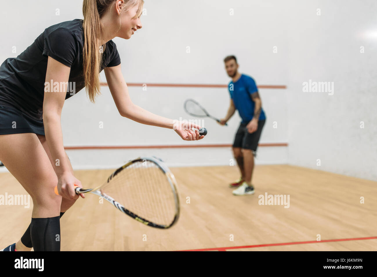 Young couple with rackets play squash game in indoor training club