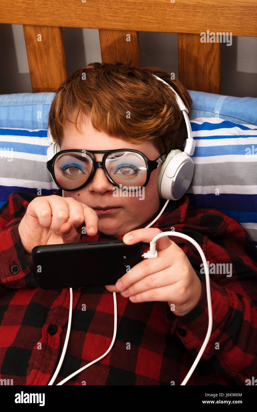 11-year old boy in bedroom using a smart phone to access the internet Stock Photo
