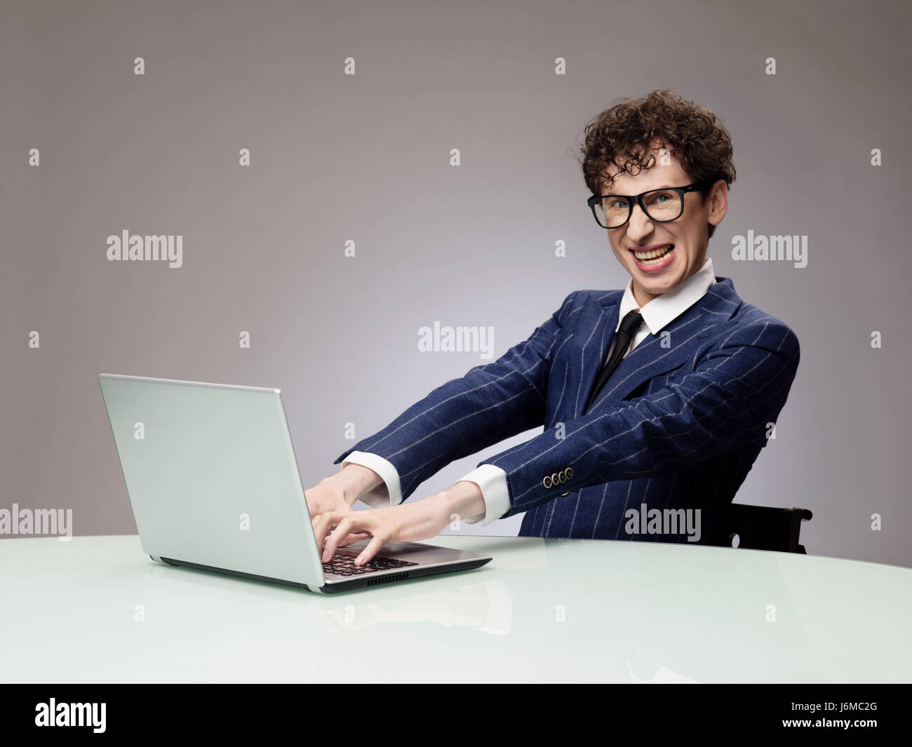Funny business man geek using laptop with evil genius facial expression Stock Photo