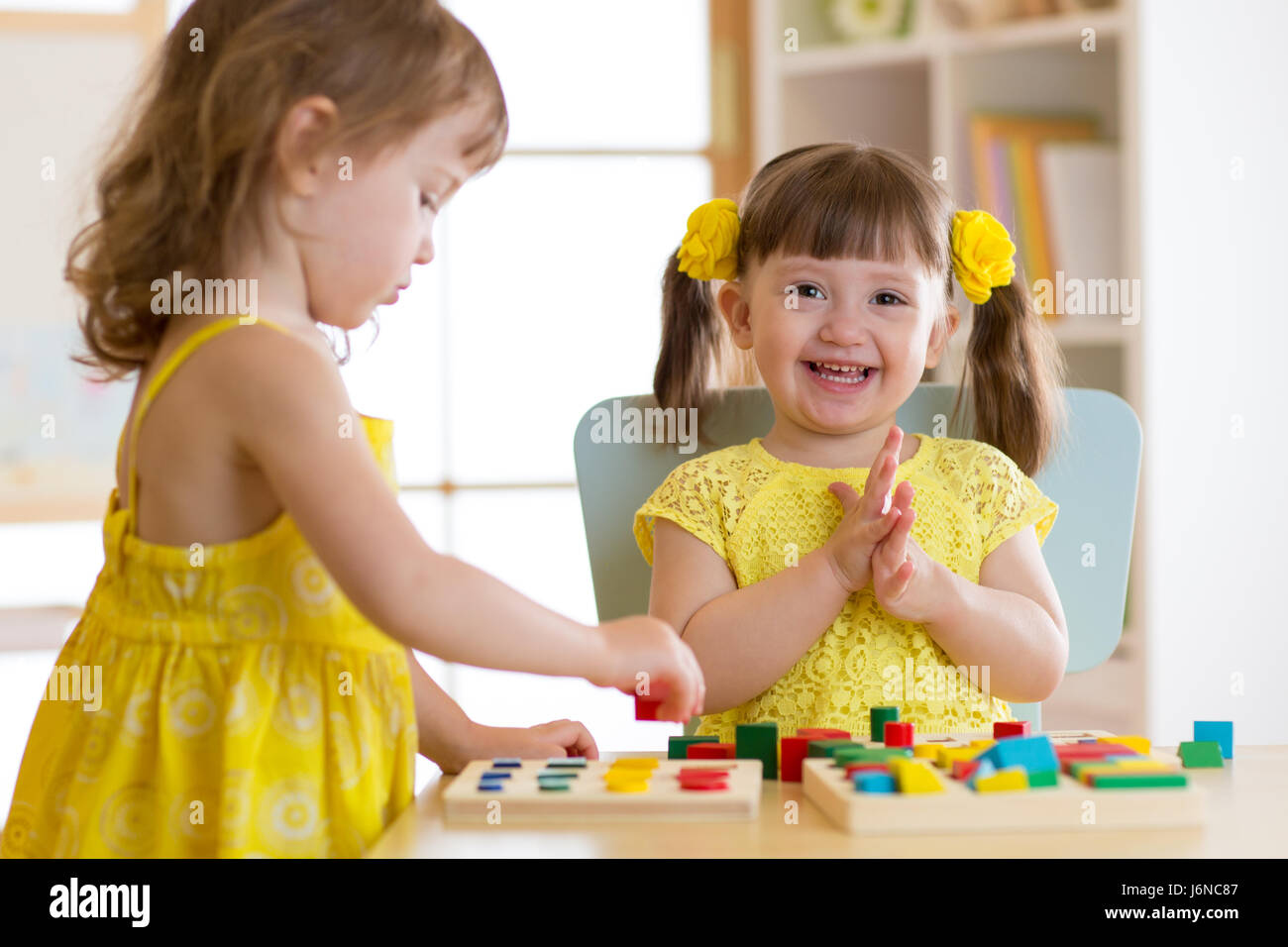 Children kids play with educational toys, arranging and sorting colors and shapes. Learning via experience conception. Stock Photo
