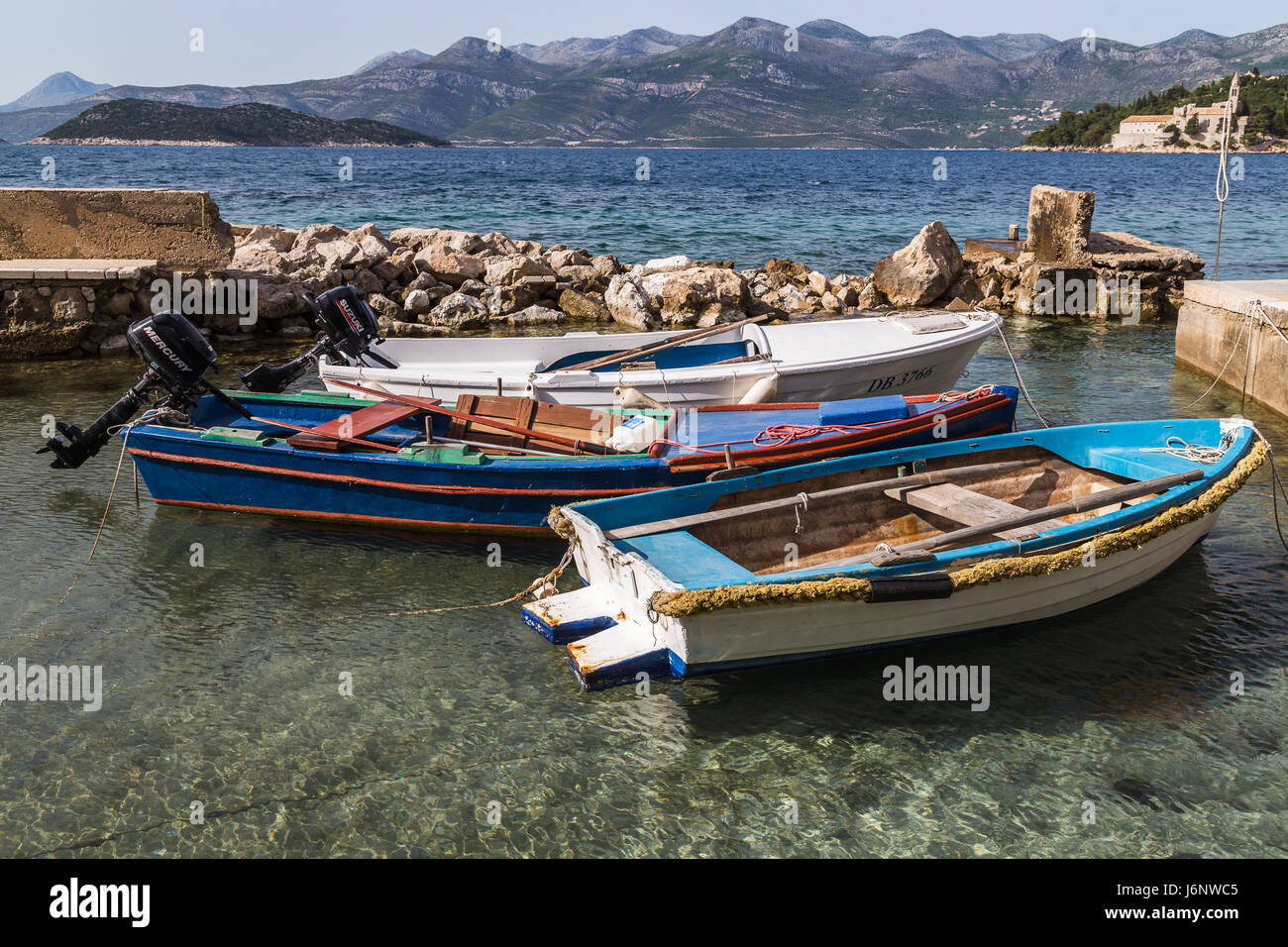 Three small fishing boats moored in a sheltered area of clear water off