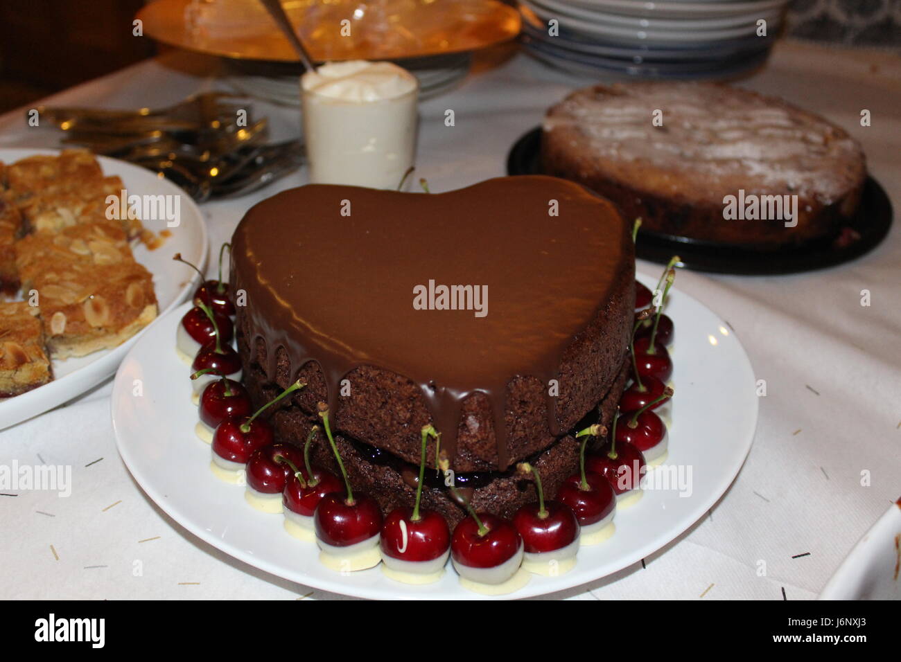 Heart shaped chocolate cake surrounded by fresh cherries dipped in ...