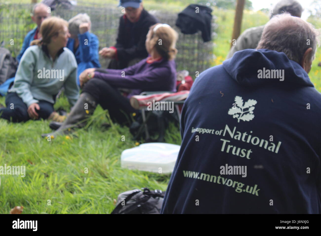 Group of volunteers for Manchester National Trust resting, with man wearing blue sweatshirt advertising the group in the foreground Stock Photo