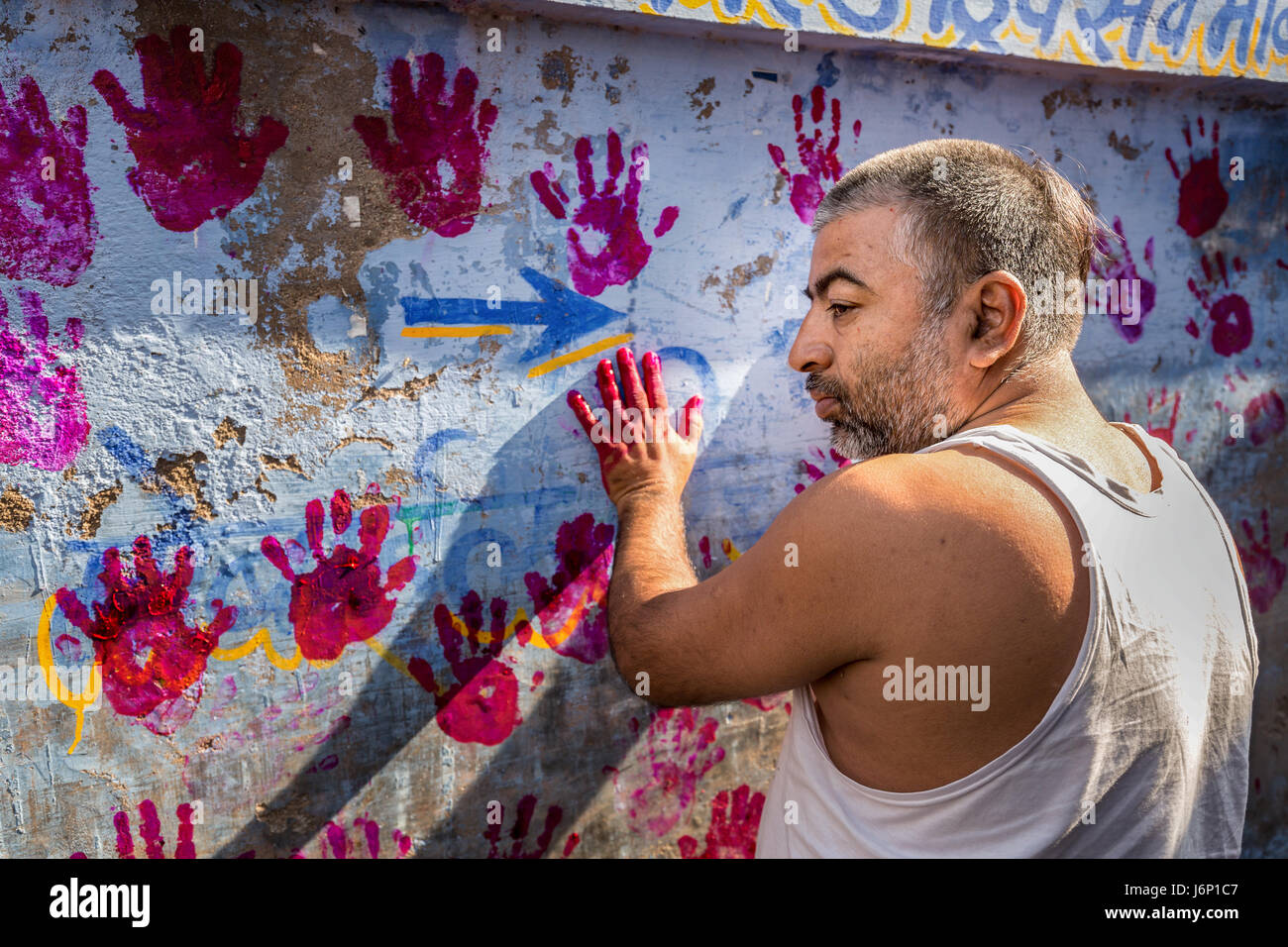 A brahmin makes red hand prints on a wall in Jodhpur, Rajasthan, India Stock Photo