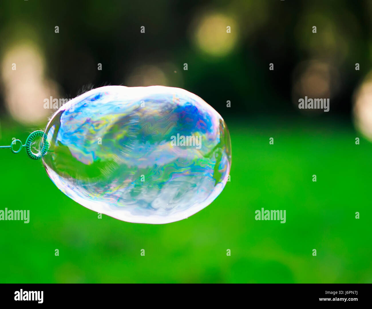 iridescent soap bubble is inflated and bursts leaving a spray Stock