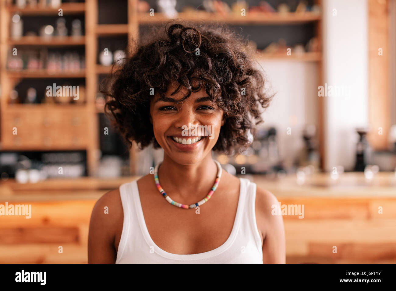 Close up portrait of beautiful young woman standing in a cafe. Smiling ...