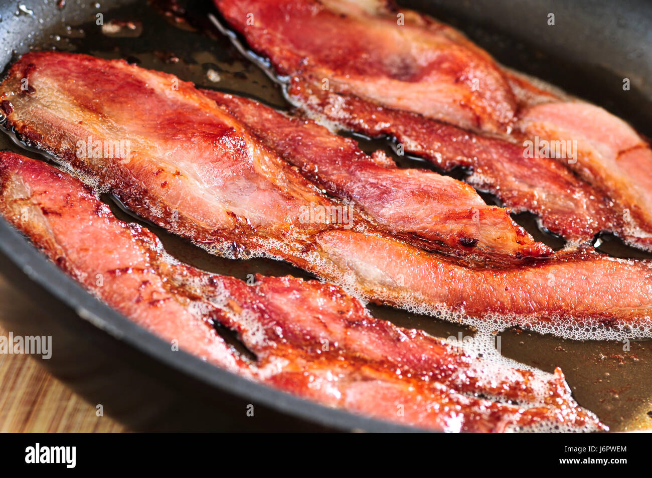 Frying pan with cooked bacon rashers on white background Stock Photo - Alamy