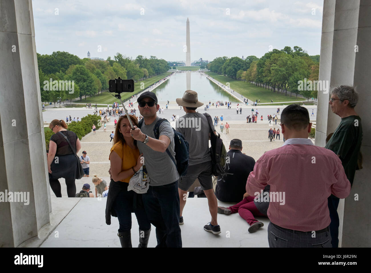 tourists taking selfies looking out of the lincoln memorial along the national mall and reflecting pool Washington DC USA Stock Photo