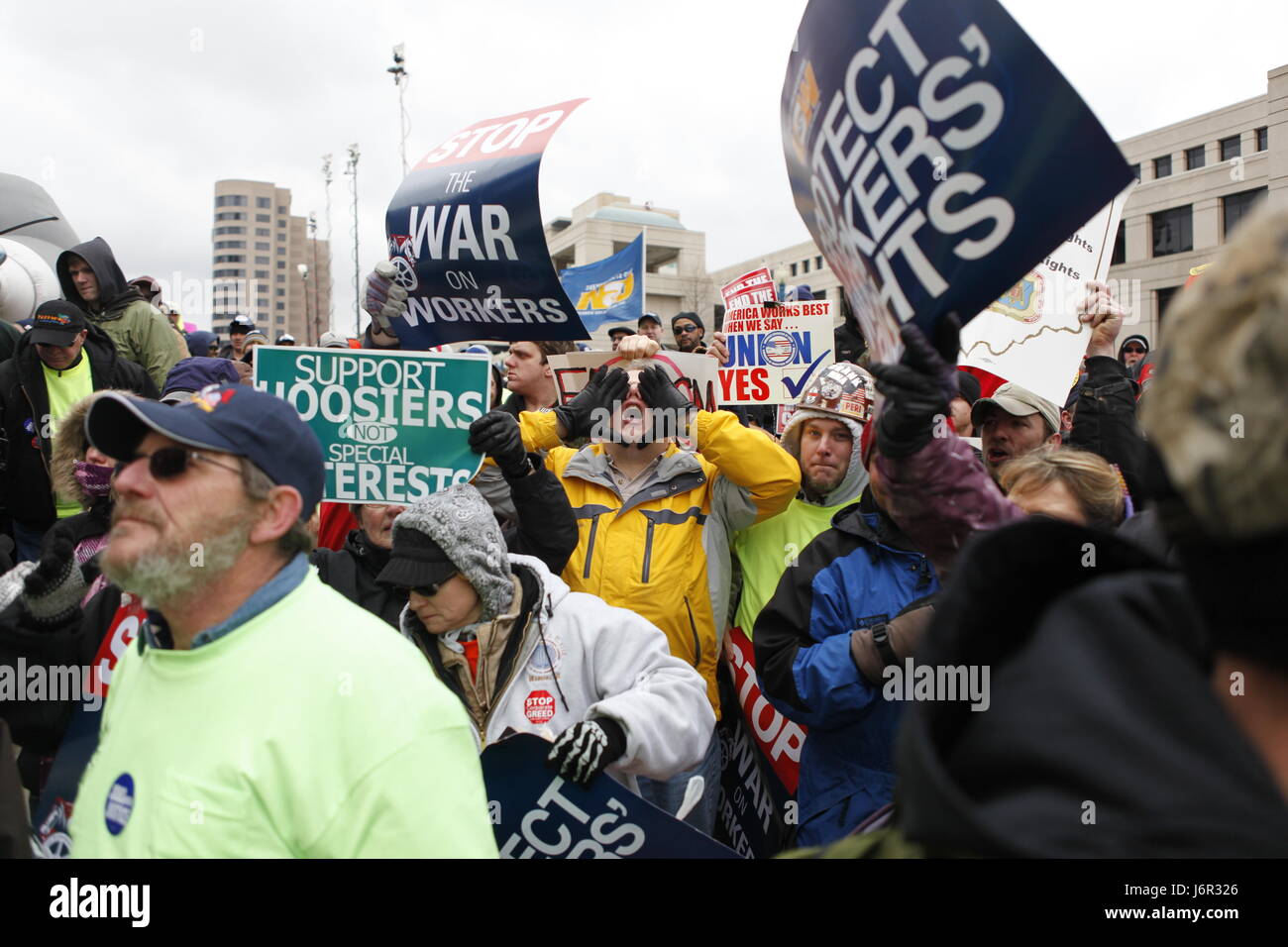 An anti-union agitator, center, who would only gave his name as Ron and who said he is from Carmel, Ind., is surrounded by angry union members as he shouts anti-union slogans during a rally attended by thousands of Union supporters and members at the Indiana Statehouse. Stock Photo