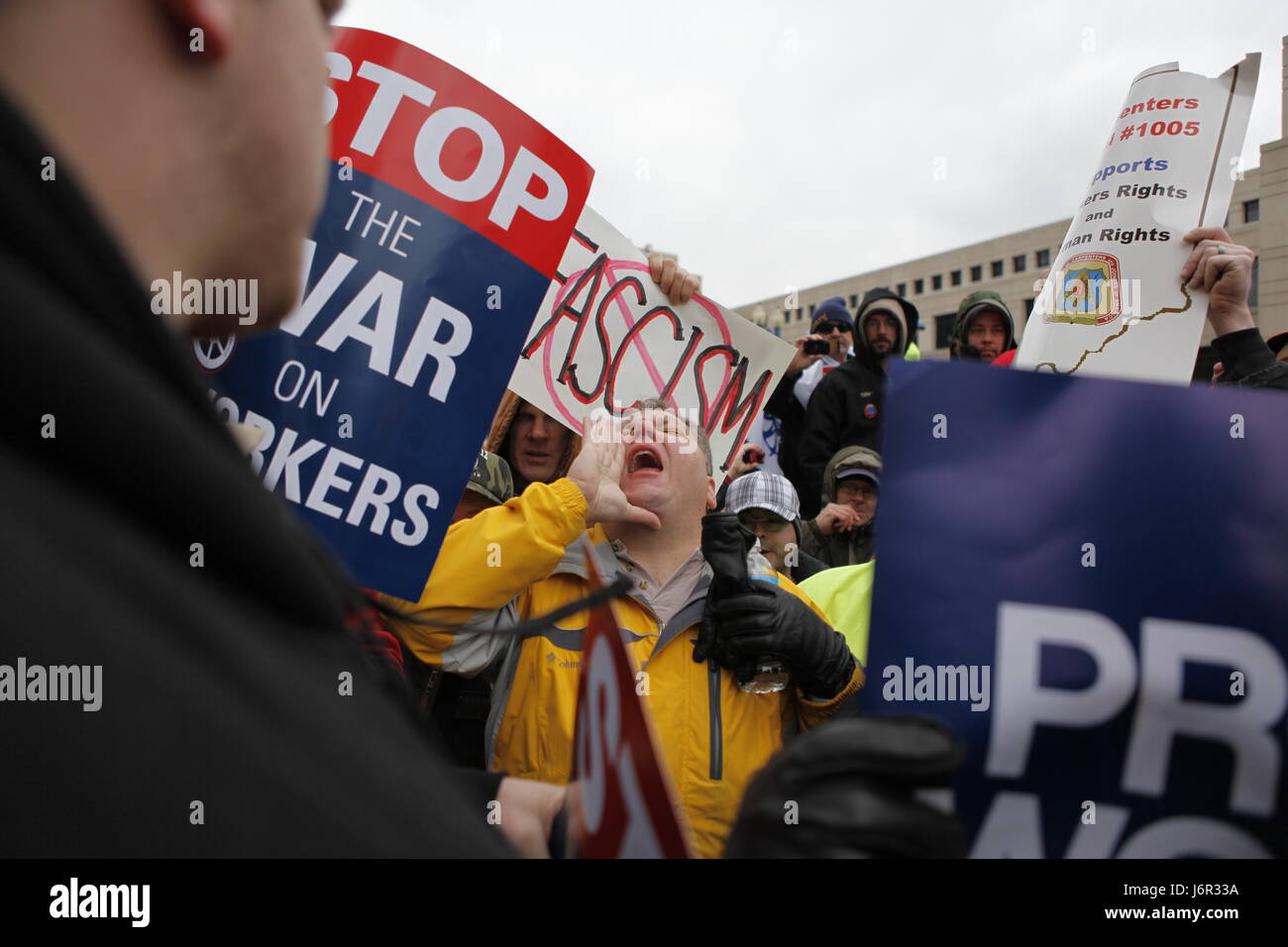 An anti-union agitator, center, who would only gave his name as Ron and who said he is from Carmel, Ind., is surrounded by angry union members as he shouts anti-union slogans during a rally attended by thousands of Union supporters and members at the Indiana Statehouse. Stock Photo