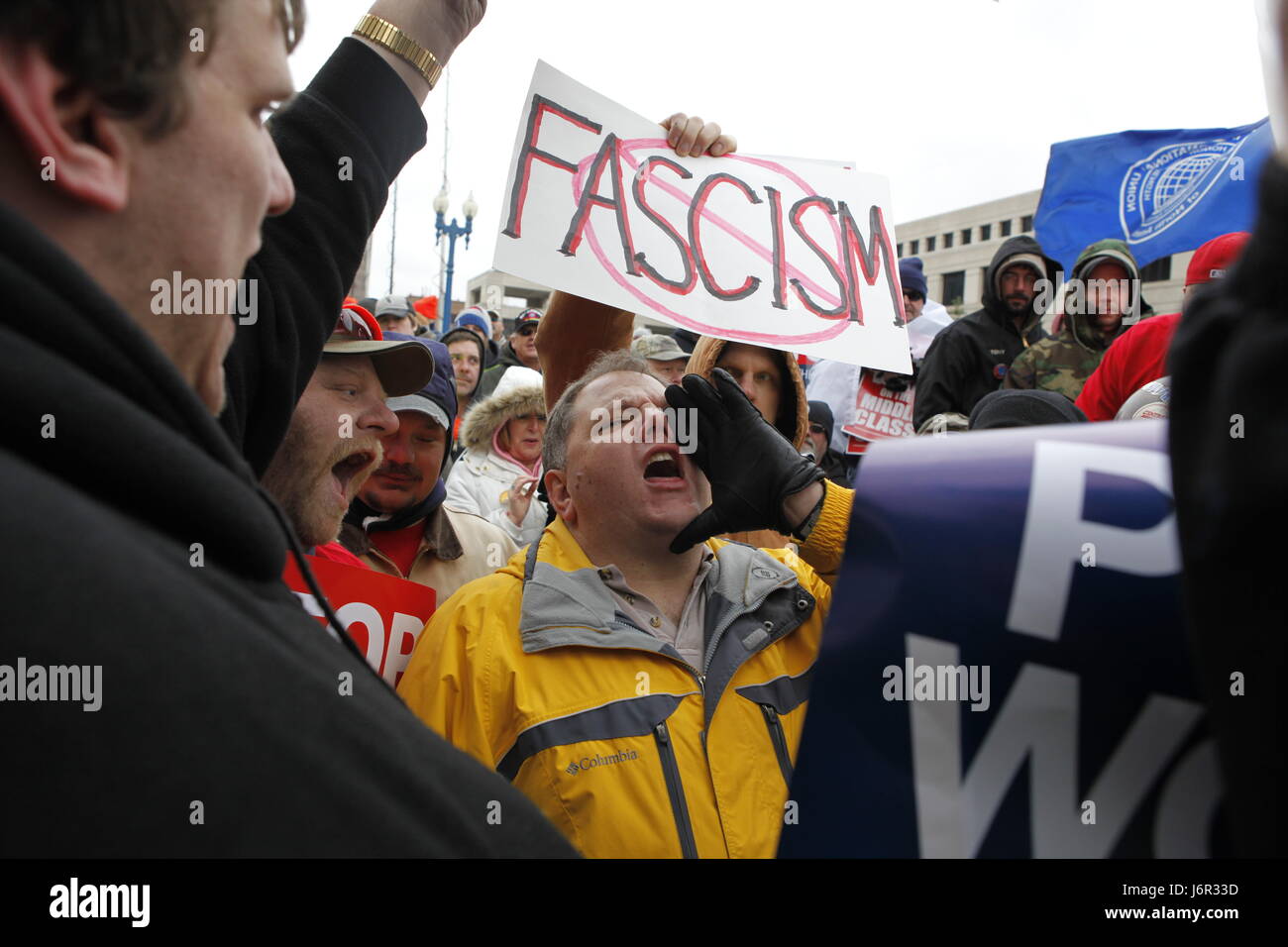 An anti-union agitator, center, who would only give his name as Ron and who said he is from Carmel is surrounded by angry union members as he shouts anti-union slogans during a rally attended by thousands of Union supporters and members at the Indiana Statehouse. Stock Photo