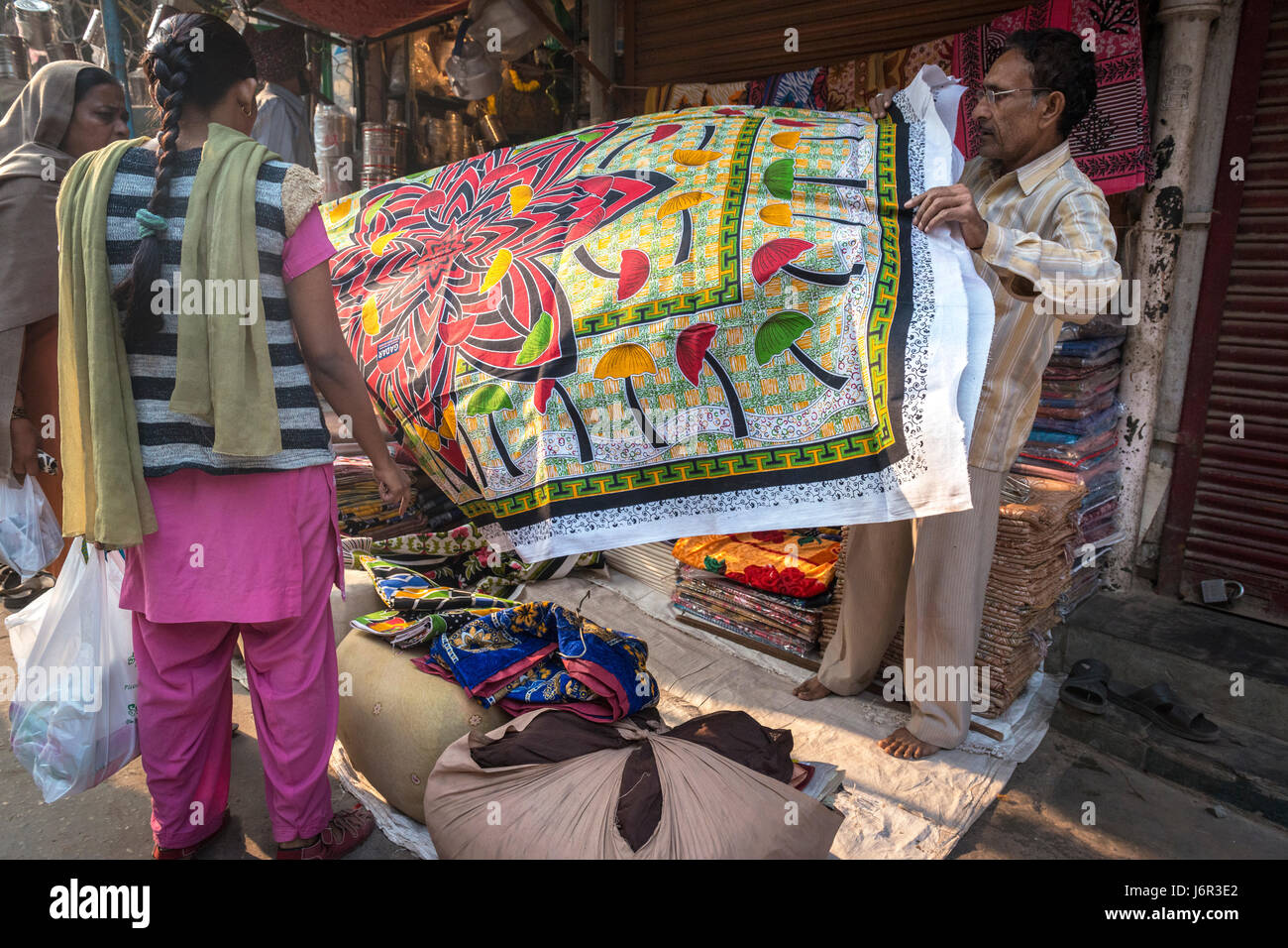 Delhi, India - 10 November 2012 - Two women buying a colorful table cloth from a street vendor, a very popular way of finding a bargin. Stock Photo