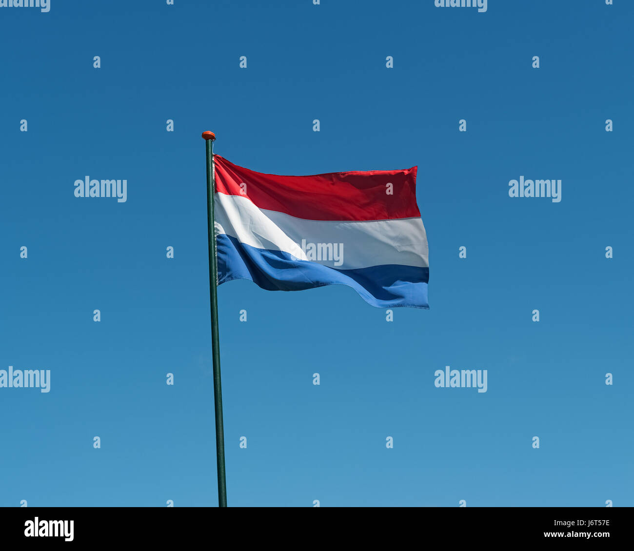 Flag of the Netherlands on flagpole waving in the wind. Netherlands national official flag on blue sky background. Patriotic symbol, banner Stock Photo