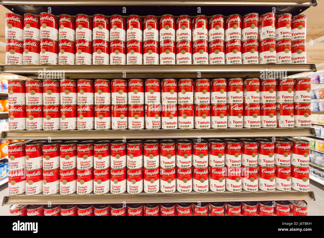 a display of Cambells tomato soup cans on display on shelves at a grocery store Stock Photo
