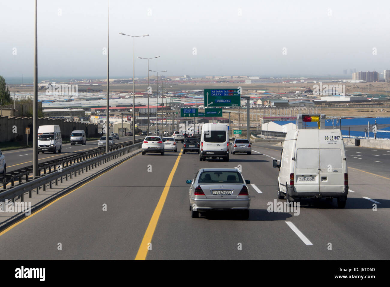 Traffic in Baku Azerbaijan, leaving the capital on the modern city bypass highway named Ipek Yolu, Silk road, Caspian sea in the background Stock Photo