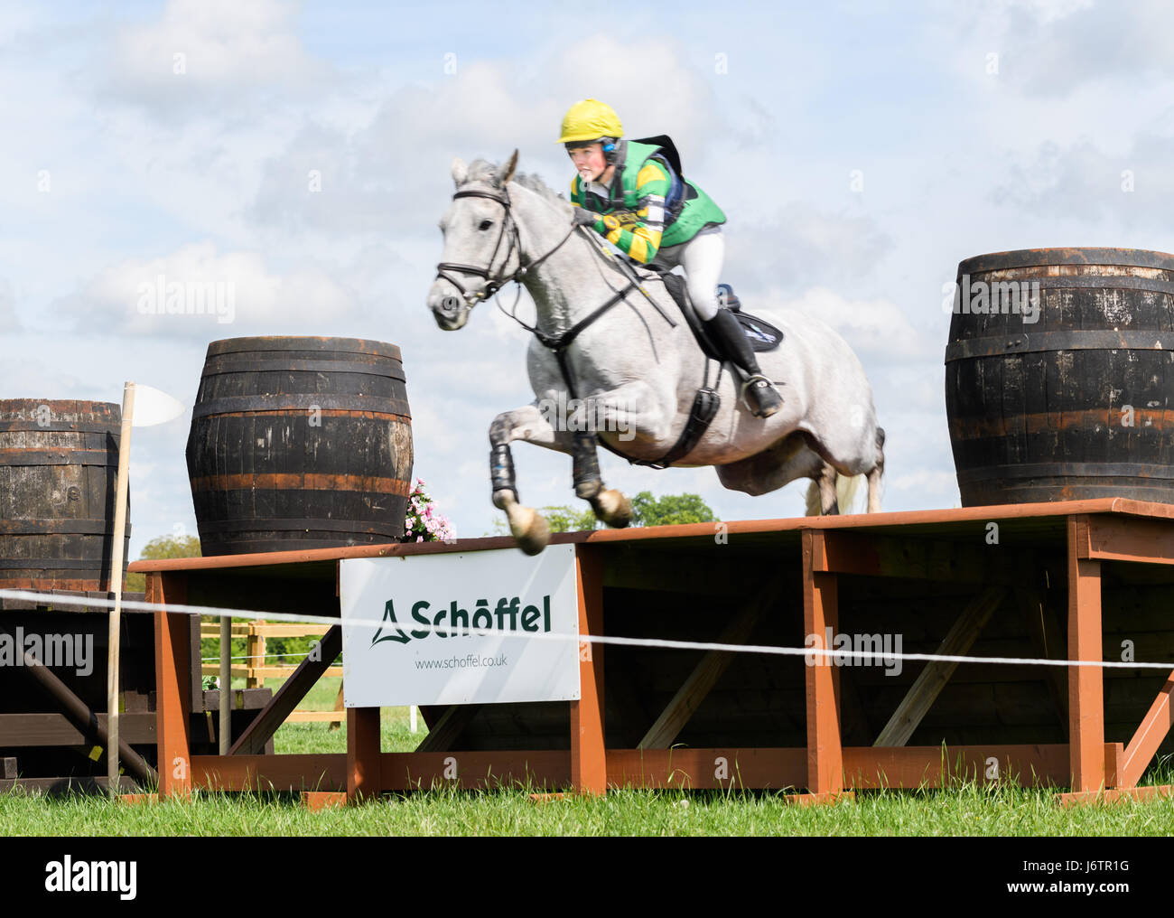 Rockingham Castle, Corby, UK. 21st May, 2017. Holly Needham and her horse Strike a Pose clear the final obstacle on a sunny day during the cross country phase of the Rockingham International Horse Trials in the grounds of the Norman castle at Rockingham, Corby, England on 21st May 2017. Credit: miscellany/Alamy Live News Stock Photo