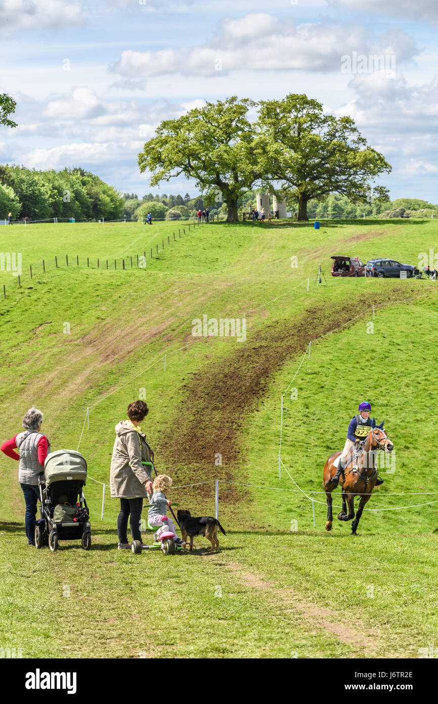 Rockingham Castle, Corby, UK. 21st May, 2017. Rebecca Pugh and her horse Master Tarka are watched by a family on a sunny day during the cross country phase of the Rockingham International Horse Trials in the grounds of the Norman castle at Rockingham, Corby, England on 21st May 2017. Credit: miscellany/Alamy Live News Stock Photo
