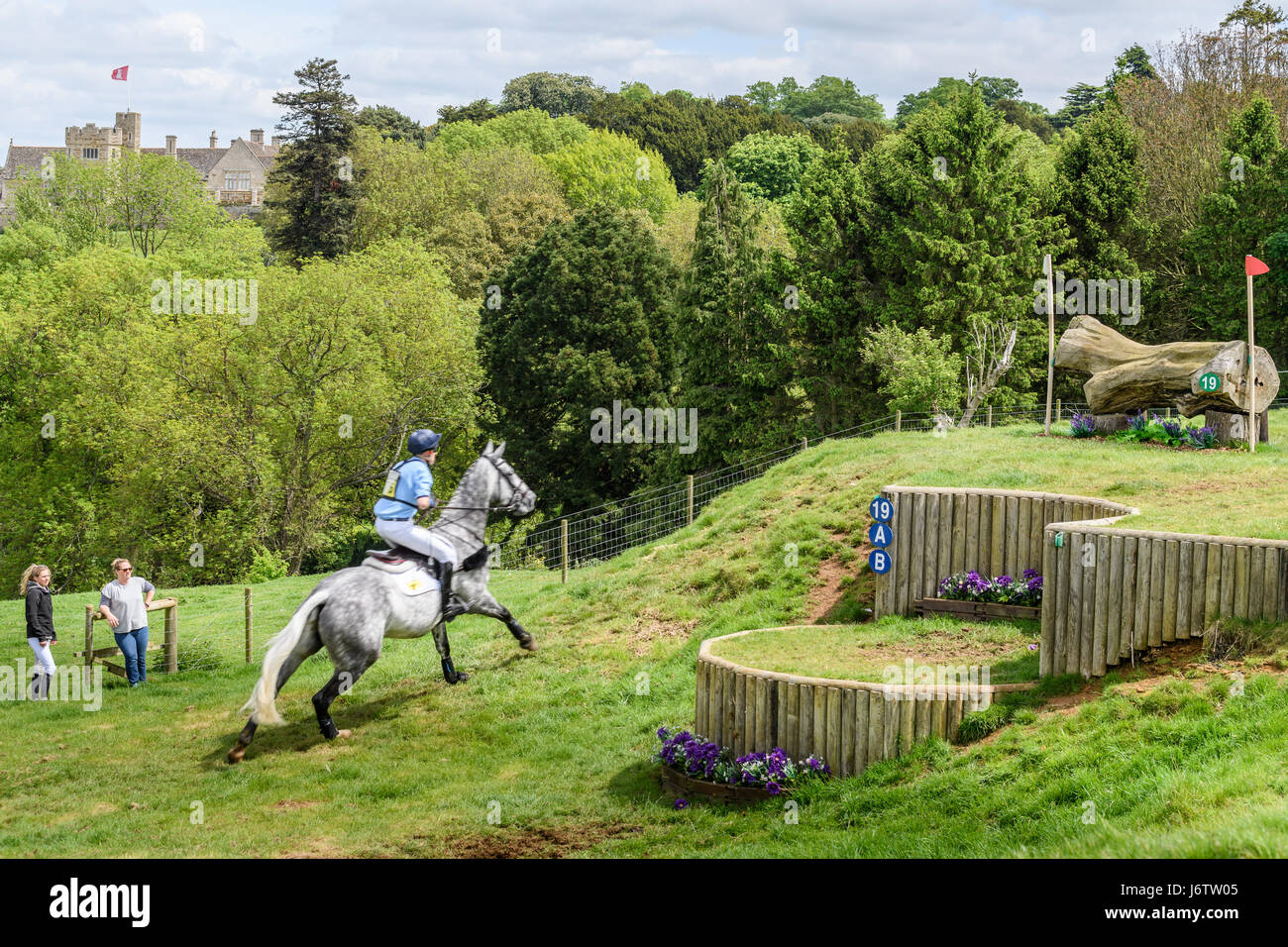 Rockingham Castle, Corby, UK. 21st May, 2017. James Rushbrooke and his horse Rowland run uphill towards a log obstacle with Rockingham castle in the background on a sunny day during the cross country phase of the Rockingham International Horse Trials in the grounds of the Norman castle at Rockingham, Corby, England on 21st May 2017. Credit: miscellany/Alamy Live News Stock Photo
