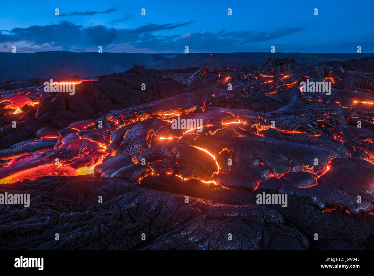 Surface flow lava oozes out of the nooks and crannies dried lava during an eruption from Kilauea volcano. Stock Photo