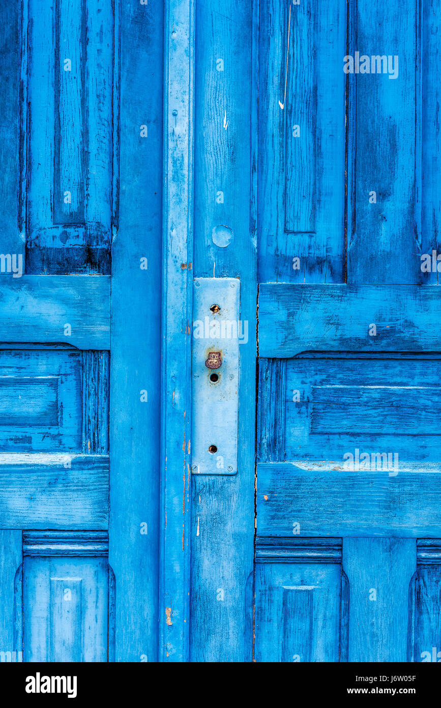 An old, antique blue door in the highlands of Hawaii show the damage that moisture has on wood. Stock Photo