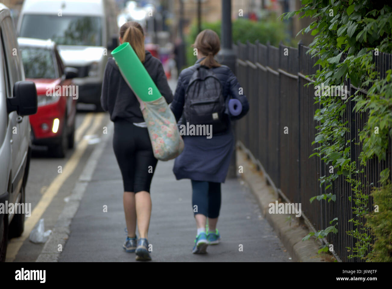 two girls on street going to yoga class with mats Stock Photo