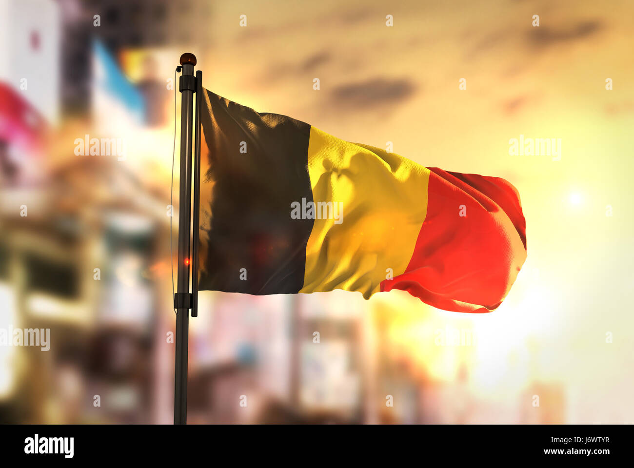 Belgium Flag Against City Blurred Background At Sunrise Backlight Stock Photo