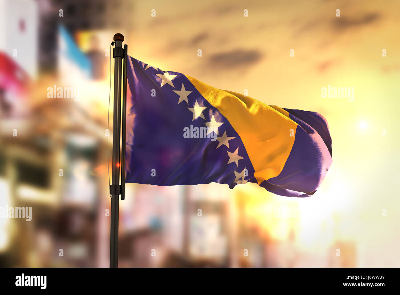 Bosnia and Herzegovina Flag Against City Blurred Background At Sunrise Backlight Stock Photo
