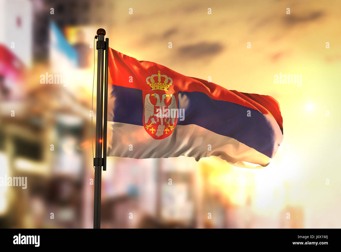 Serbia Flag Against City Blurred Background At Sunrise Backlight Stock Photo