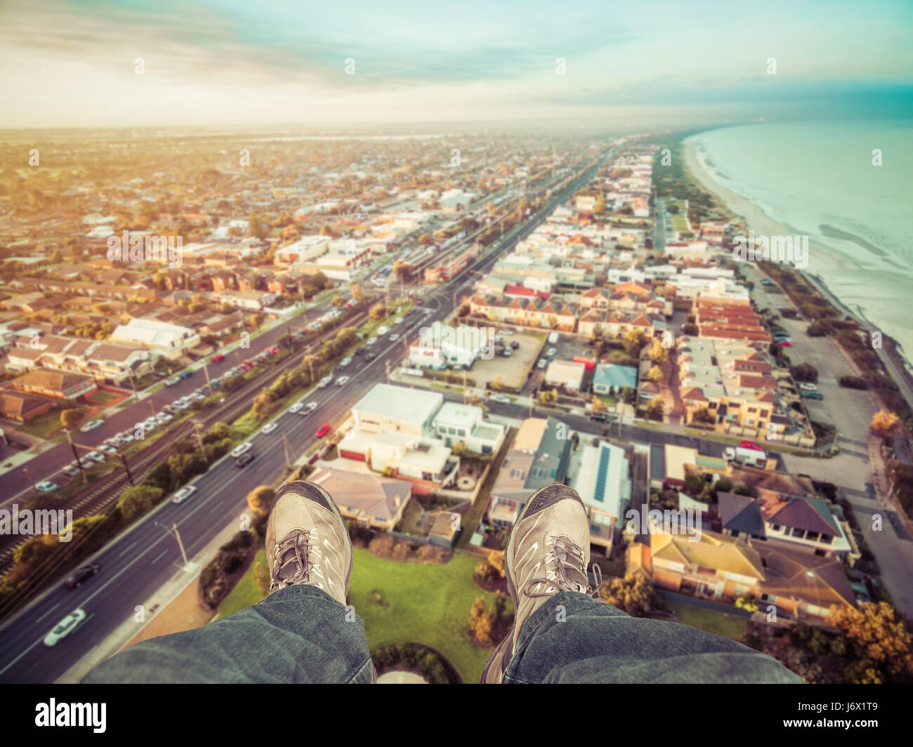 Feet hanging out of helicopter above Patterson Lakes suburb and Nepean Highway at sunrise. Melbourne, Victoria, Australia. Stock Photo