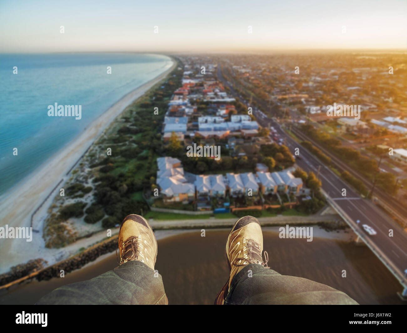 Feet hanging out of helicopter above Patterson Lakes suburb and Nepean Highway at sunrise. Melbourne, Victoria, Australia. Stock Photo