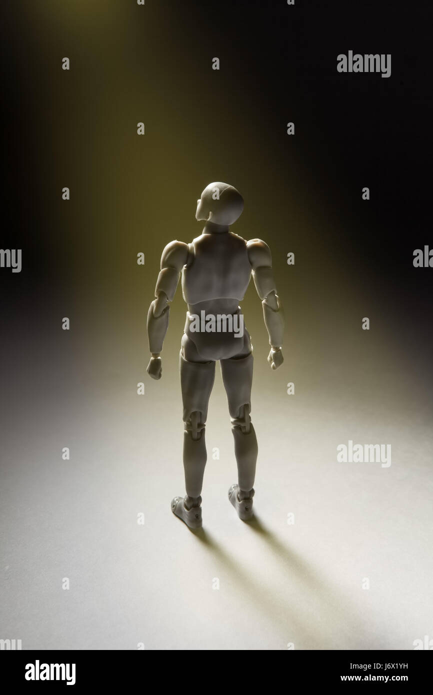 Man figurine standing in powerful pose looking up with beam of light illuminating it. Vertical conceptual image with copy space. Stock Photo