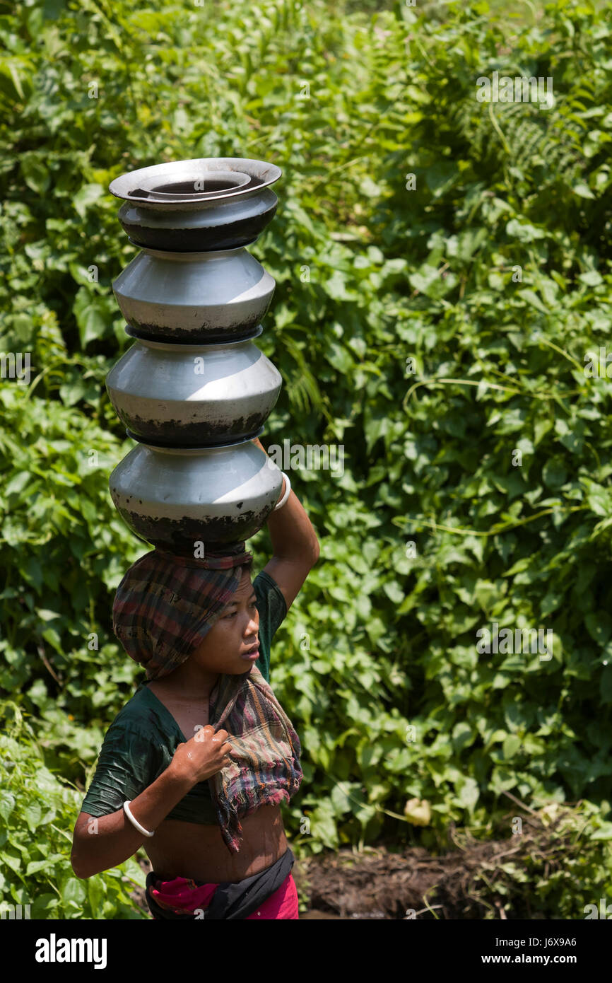 An ethnic woman carries water pots on head. Khagrachari, Bangladesh. Stock Photo