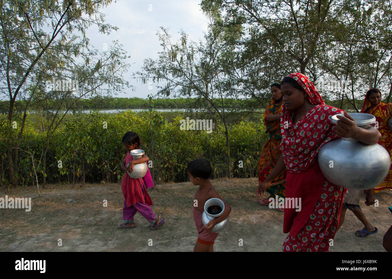 Women and children carry pitcher of drinking water at Burigoalini. Satkhira, Bangladesh Stock Photo