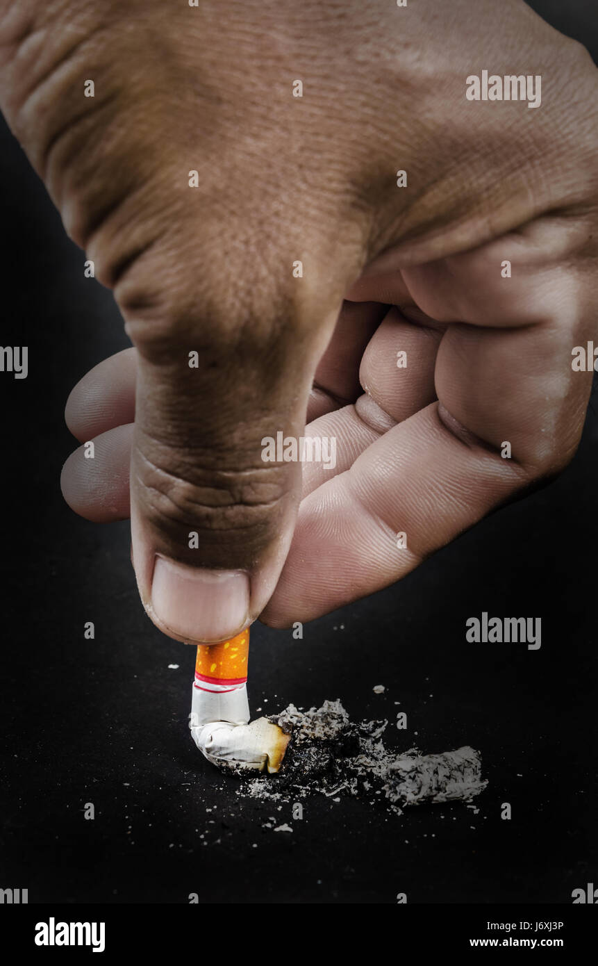 cigarette upside down in pack Upside down man hand holding a cigarette with smoke on black background  Stock Photo