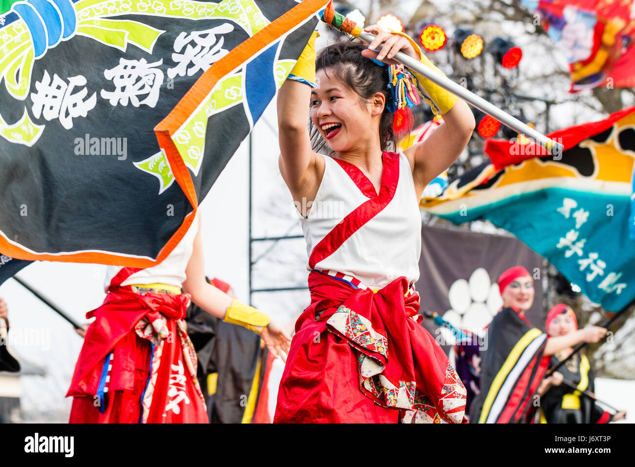 Hinokuni Yosakoi dance festival in Kumamoto, Japan. Young woman laughing, holding flag pole with both hands waving it around above her head. Stock Photo