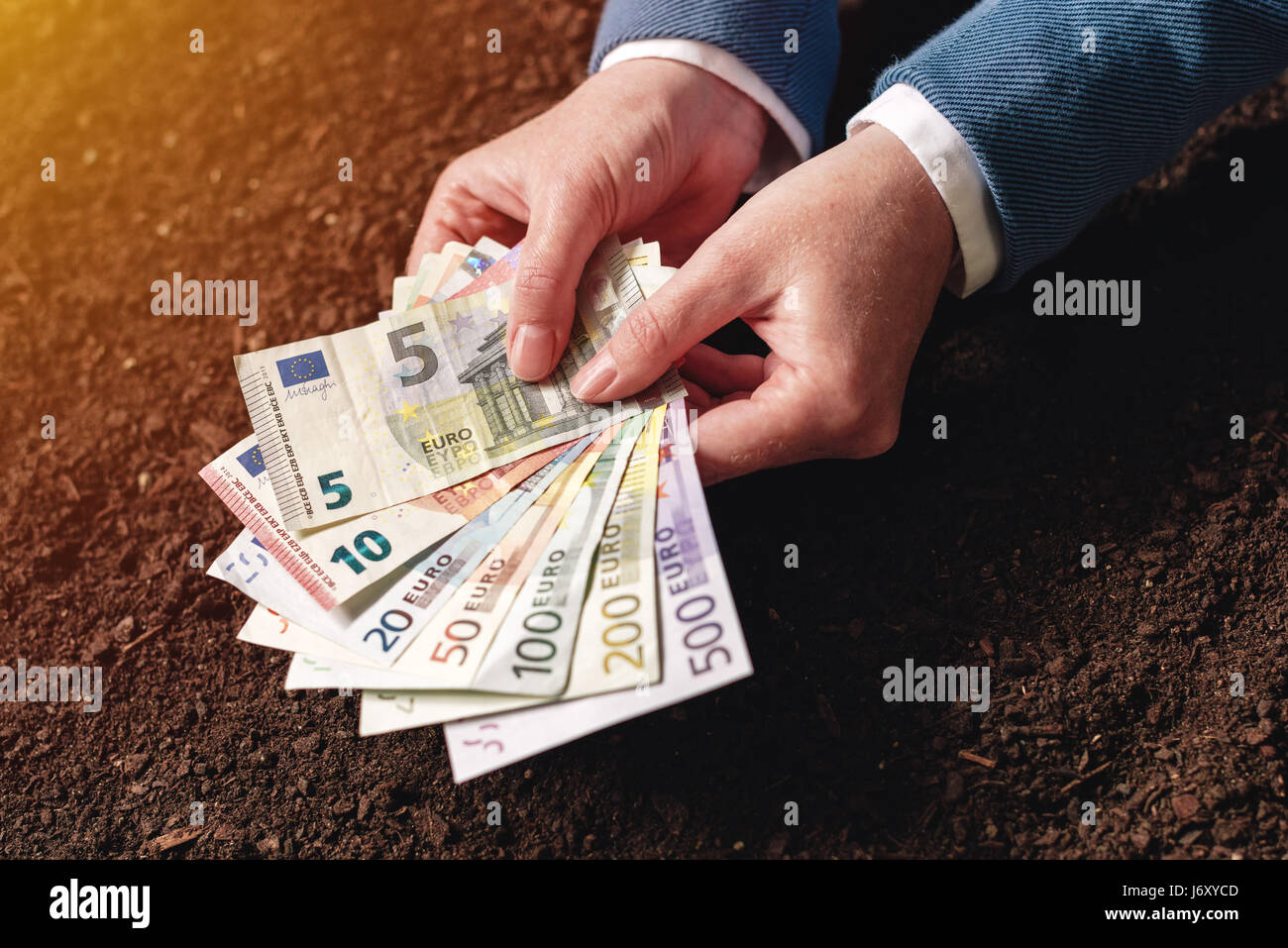 Bank loan for agricultural activity in euro banknotes, businesswoman in elegant business suit with european currency cash money over fertile soil Stock Photo