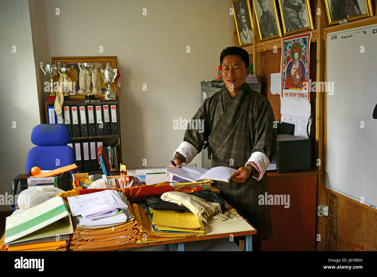 Pricdipal of Phobjikha elementary school in his office presenting book with donations from visitors, Bhutan Stock Photo