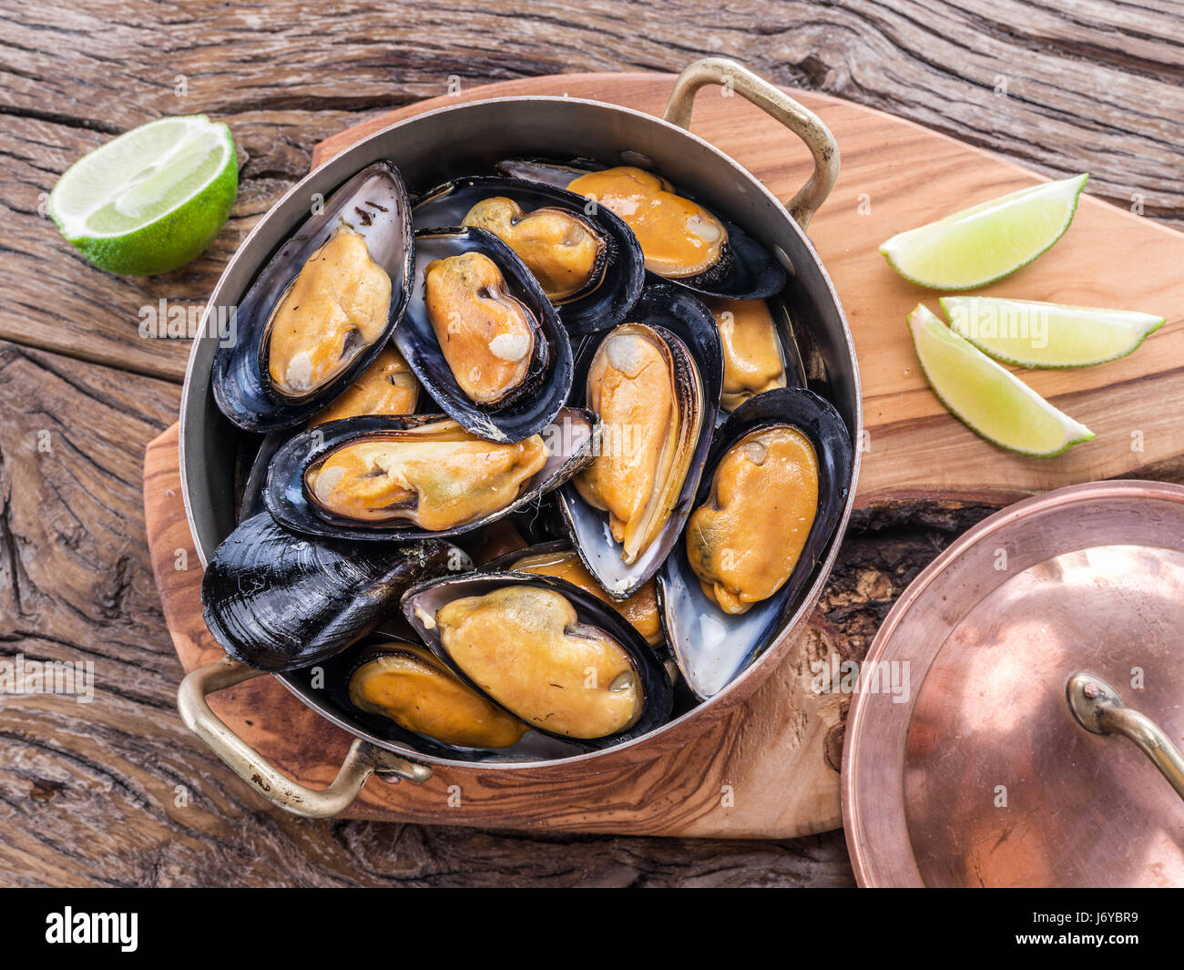 Boiled mussels in copper pan on the wooden table. Stock Photo