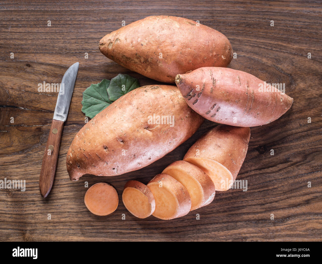 https://c8.alamy.com/comp/J6YC6A/sweet-potatoes-on-the-old-wooden-table-J6YC6A.jpg