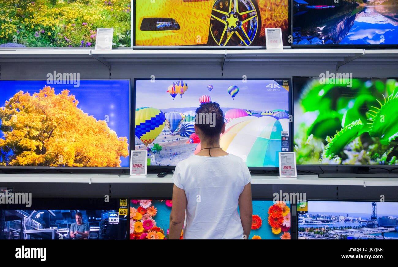 Woman looking TV screens in electrical store. Stock Photo